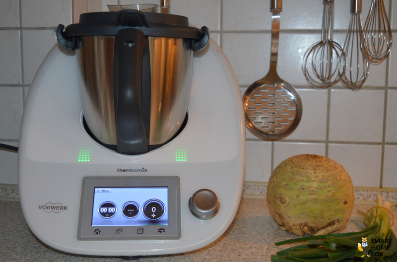 Weißer Thermomix TM5 neben Sellerie und Frühlingszwiebeln von vorne